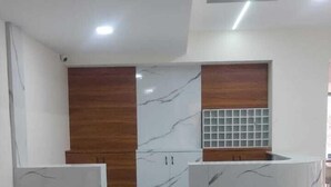 A reception area with marble countertops, wooden paneling, and a tiled backsplash. - Hotel Iris Executive (Paud)