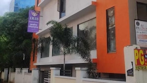 A multi-story building with orange and white exterior walls, multiple windows, and a signboard. - Hotel Iris Executive (Paud)