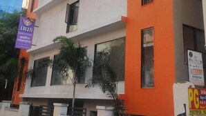 A multi-story building with a white and orange facade, featuring multiple windows and balconies. - Hotel Iris Executive (Paud)
