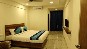 A hotel room with a bed, a ceiling fan, an air conditioning unit, a TV mounted on the wall, and a marble floor. - Hotel Iris Executive (Paud)