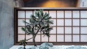 Una habitación tradicional japonesa con suelo de tatami, un panel shoji y un bonsai.
