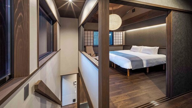 Habitación de hotel moderna con una cama grande, un escritorio y vistas de la ciudad a través de amplios ventanales.