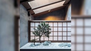 Una habitación de diseño minimalista, con un ventanal de diseño de cuadrícula, un bonsái y un jardín de rocas.