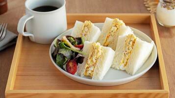 A tray with a plate of sandwiches, a cup of coffee, and a small salad.