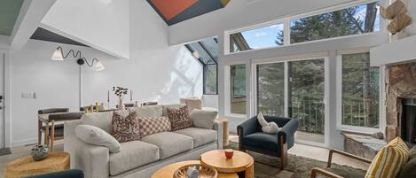 Un salon spacieux avec un haut plafond, de grandes fenêtres et une cheminée.