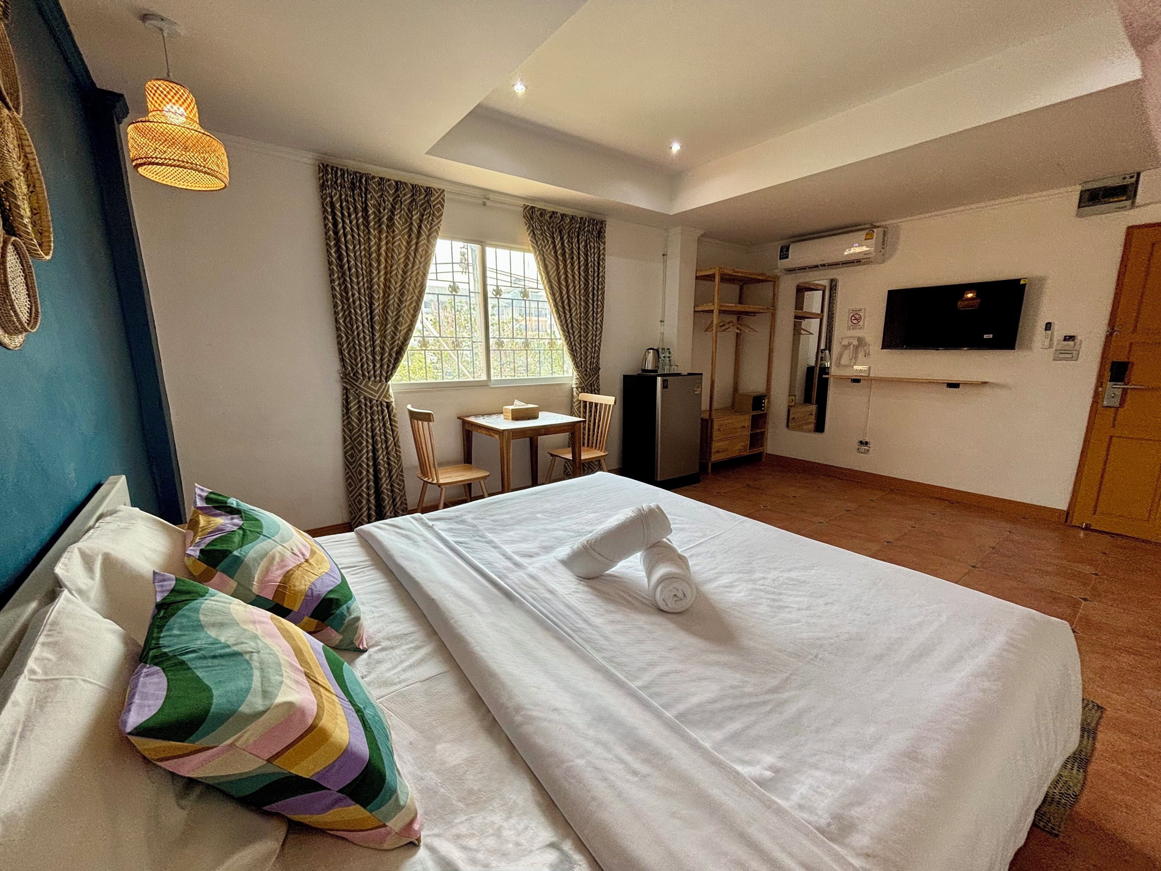 A hotel room with a bed, a desk, a chair, a television, and a wardrobe.