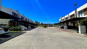 Un parking bordé de bâtiments modernes, un ciel d’un bleu éclatant et un lampadaire.