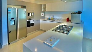 Une cuisine moderne dotée d’un îlot central, d’appareils électroménagers en acier inoxydable et d’un four encastré.