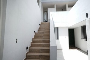 A staircase leading to a second-floor area with a white exterior wall and a window.