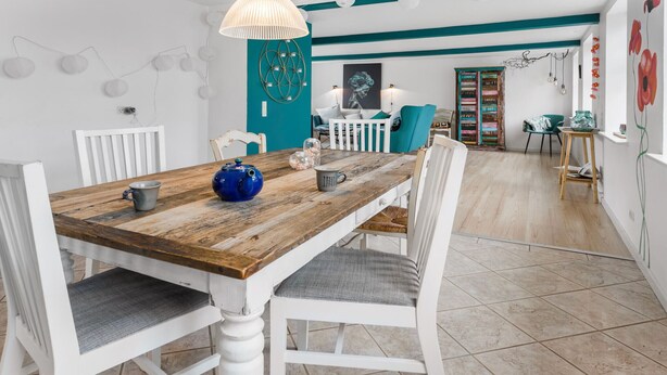 A dining area with a wooden table, white chairs, and a teal accent wall. - Nice home in Rønne with WiFi (Rønne)
