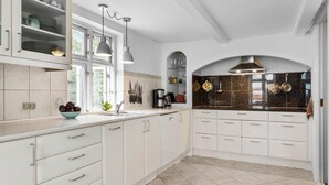A kitchen with white cabinets, a tiled backsplash, and a window providing natural light. - Nice home in Rønne with WiFi (Rønne)