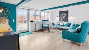 A modern living room with a teal color scheme, a blue rocking chair, a sofa, and a coffee table. - Nice home in Rønne with WiFi (Rønne)