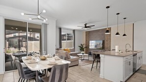 Une cuisine moderne dotée d’un îlot central, d’un coin repas avec des chaises et d’une grande fenêtre.
