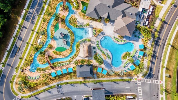 Vue aérienne d’un complexe hôtelier doté de plusieurs piscines, d’un terrain de golf et d’un vaste parking.