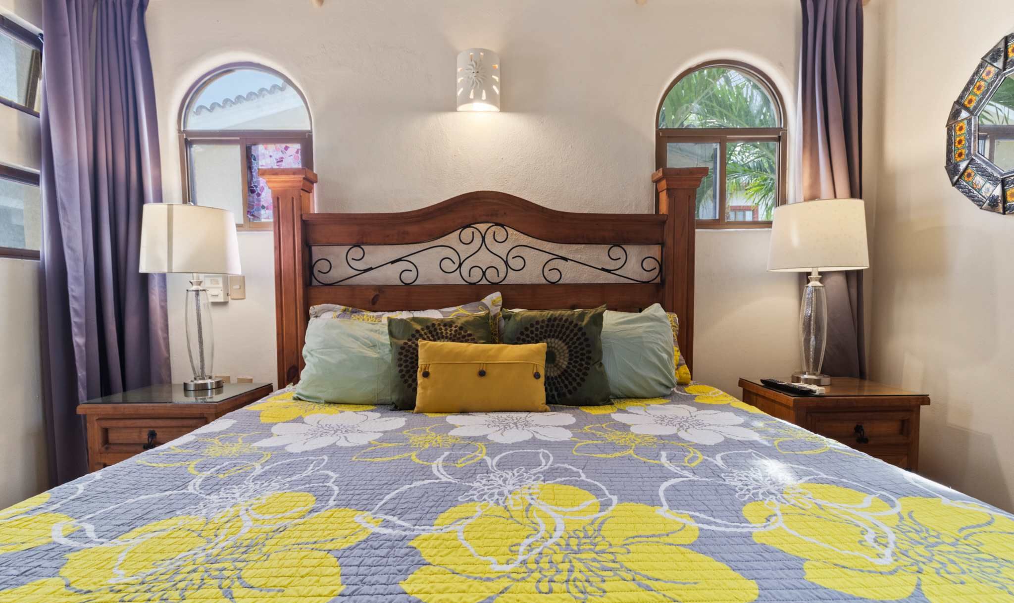 A bed with a floral bedspread, two bedside lamps, and a decorative wall light.