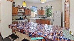 A kitchen with a colorful tiled island, wooden cabinets, a microwave, and a refrigerator. - Casa Sandy - Private Golden Zone Villa with Pool (Bucerías)