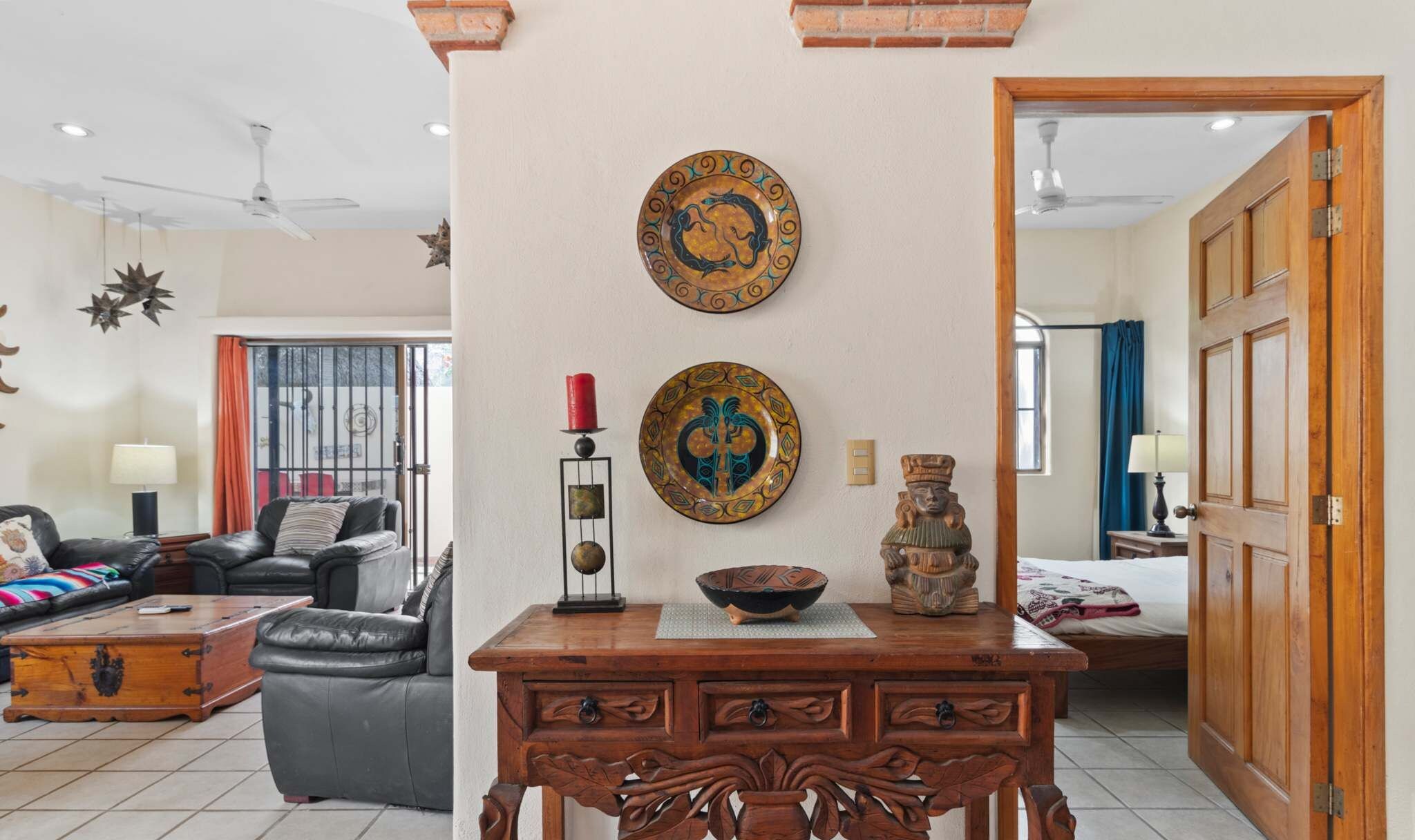 A living room with a sofa, a wooden coffee table, decorative plates, and a small statue.