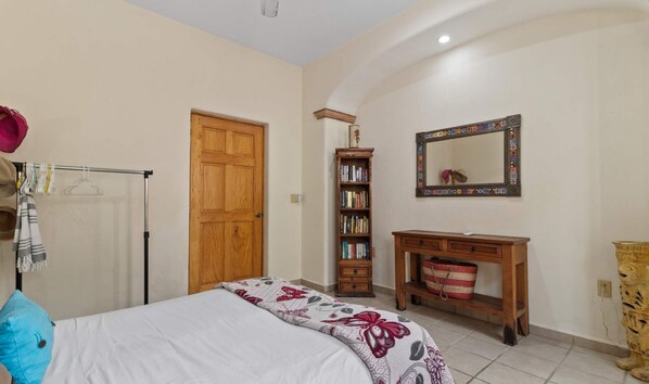 A bedroom with a bed, a wooden wardrobe, a bookshelf, a mirror, and a small wooden cabinet. - Casa Sandy - Private Golden Zone Villa with Pool (Bucerías)