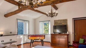 Una sala de estar acogedora con mesa de fútbol, televisor y techo de madera.