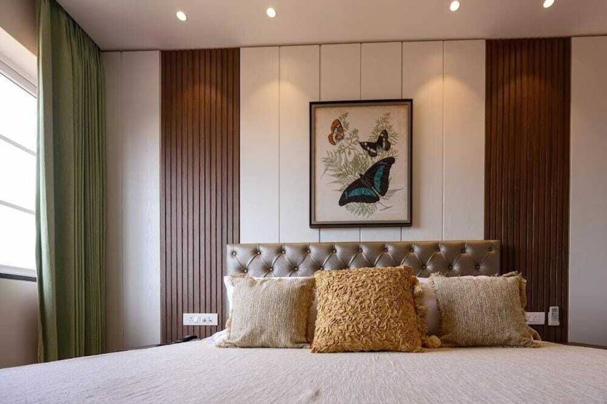 Une chambre d’hôtel avec un grand lit, une tête de lit capitonnée et, au-dessus, un tableau représentant un papillon encadré.