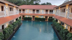 Un hôtel doté d’une piscine centrale, de nombreux balcons et d’une cour intérieure bordée de verdure.