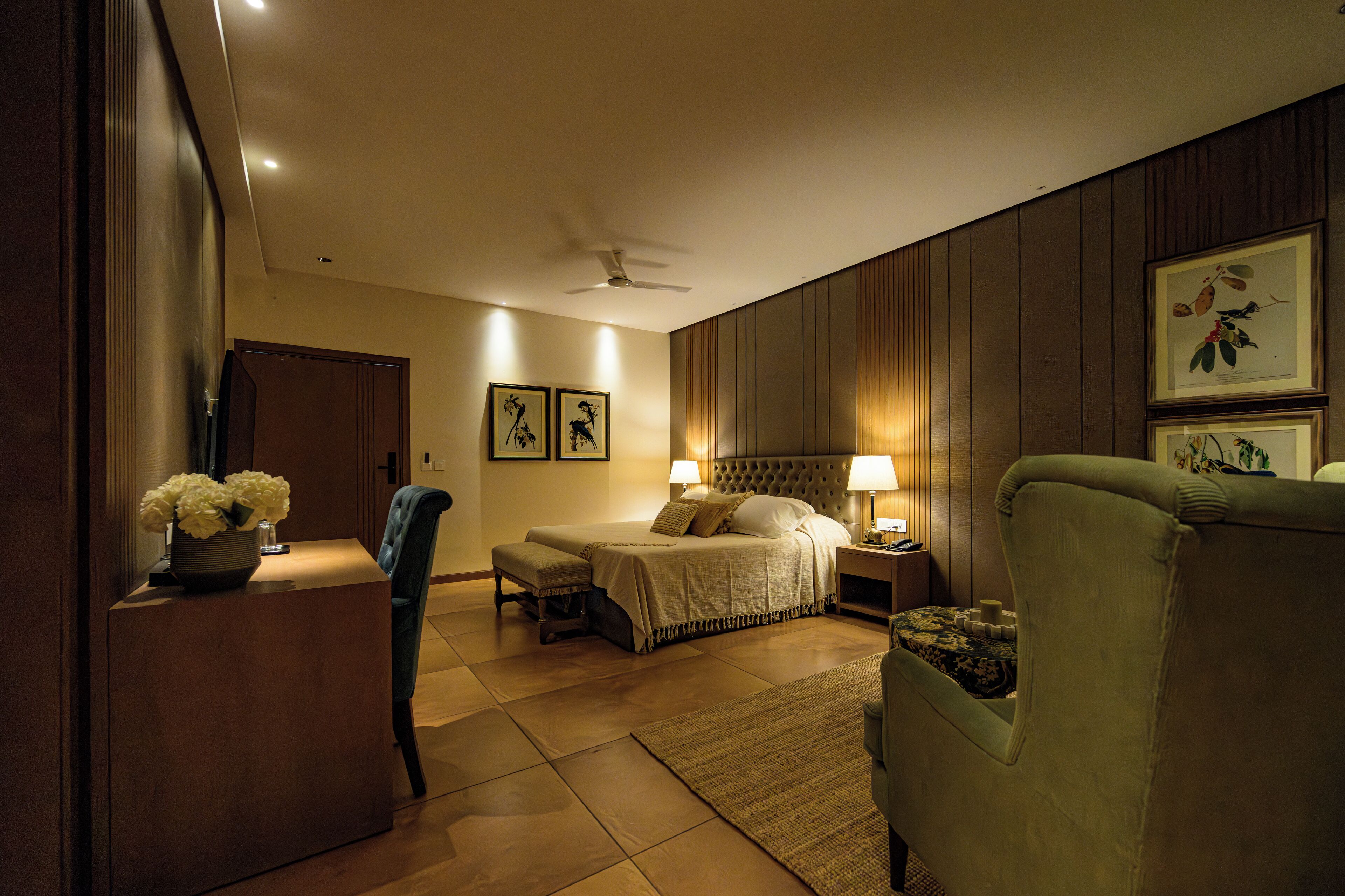 Una habitación de hotel con cama, mesitas de noche, escritorio, silla y ventilador de techo.