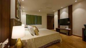 Une chambre d’hôtel avec un lit, une télévision, un bureau et une fenêtre avec des rideaux.