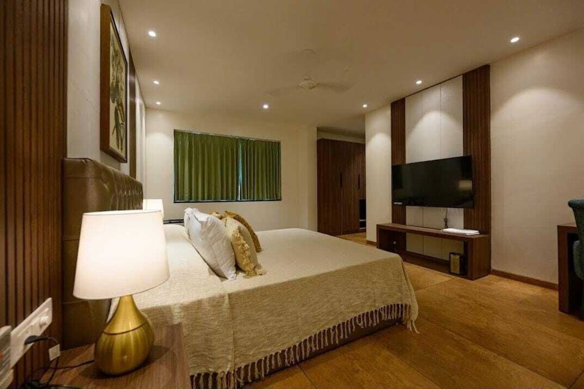 Une chambre d’hôtel avec un lit, une télévision, un bureau et une fenêtre avec des rideaux.