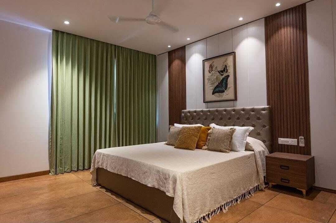 A bedroom with a large bed, a nightstand, a ceiling fan, and a wall-mounted artwork.