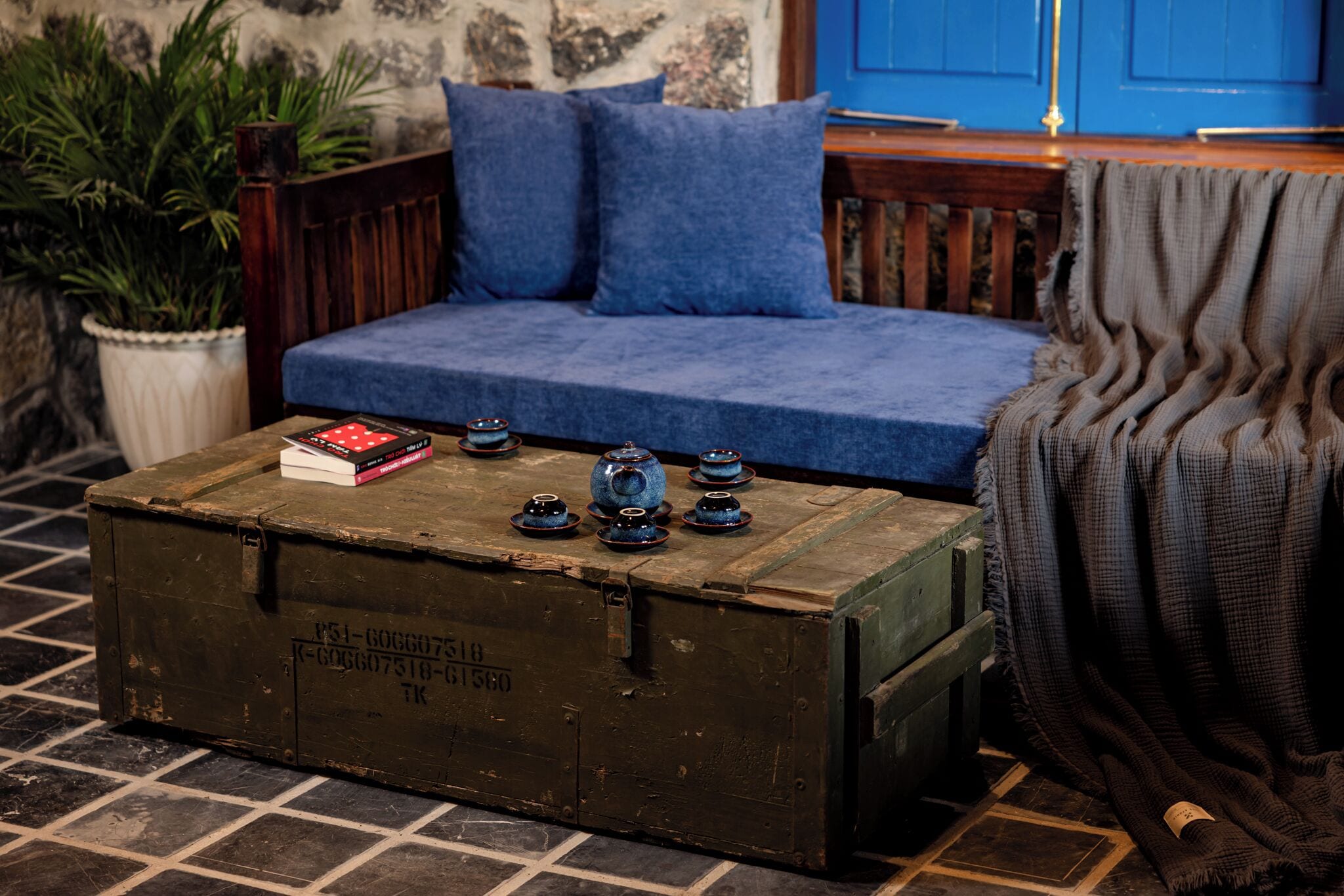 Una habitación acogedora con un cofre de madera, un sofá azul y una planta en maceta.