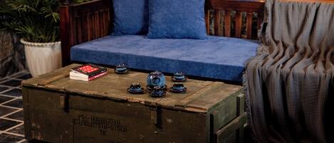 Una habitación acogedora con un cofre de madera, un sofá azul y una planta en maceta.