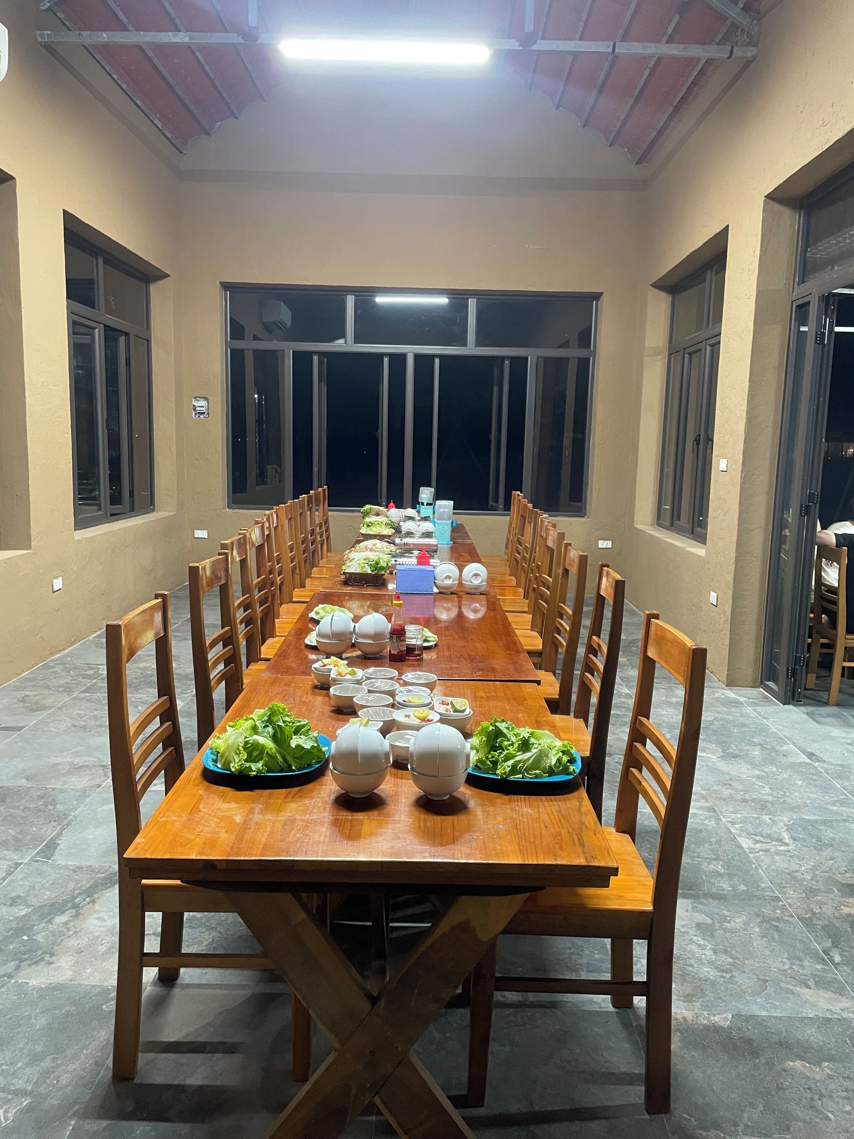 A long dining table with chairs, set for a meal.