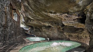 A spa area with two hot tubs set in a cave-like environment, surrounded by stone walls. - Chay Mountain Retreat Ninh Binh (Hoa Lu)