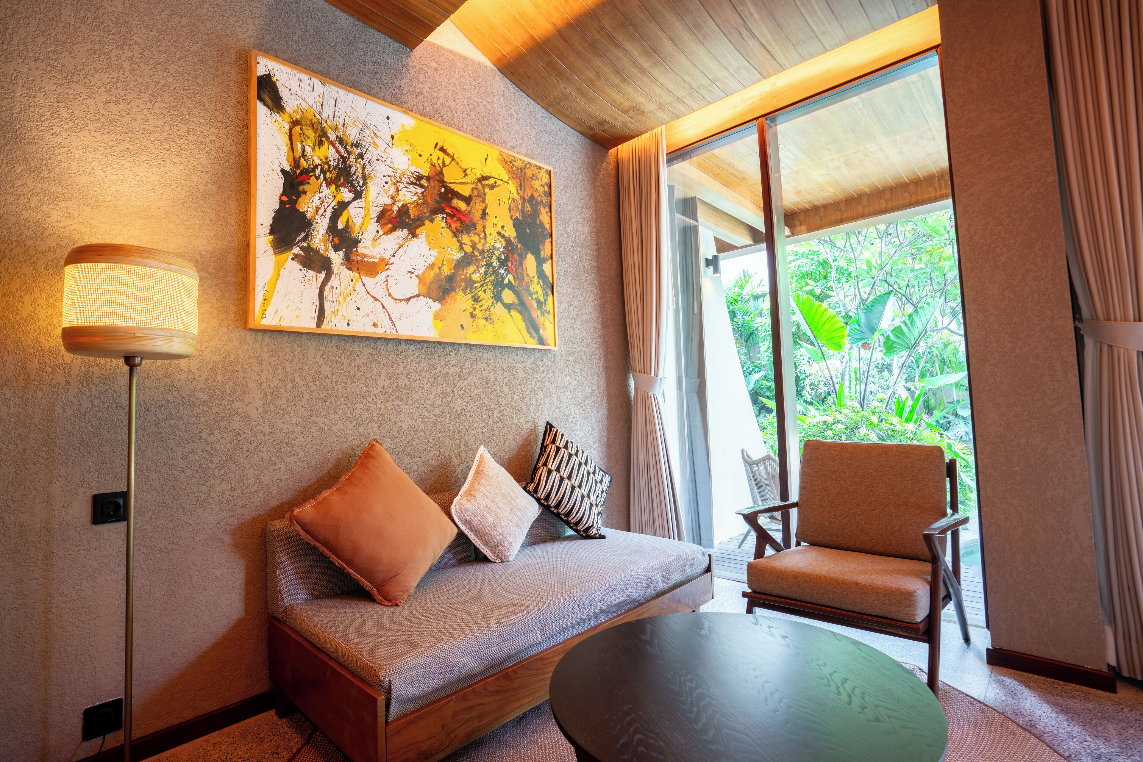 A modern room with a sofa, a chair, a table, and a painting on the wall.