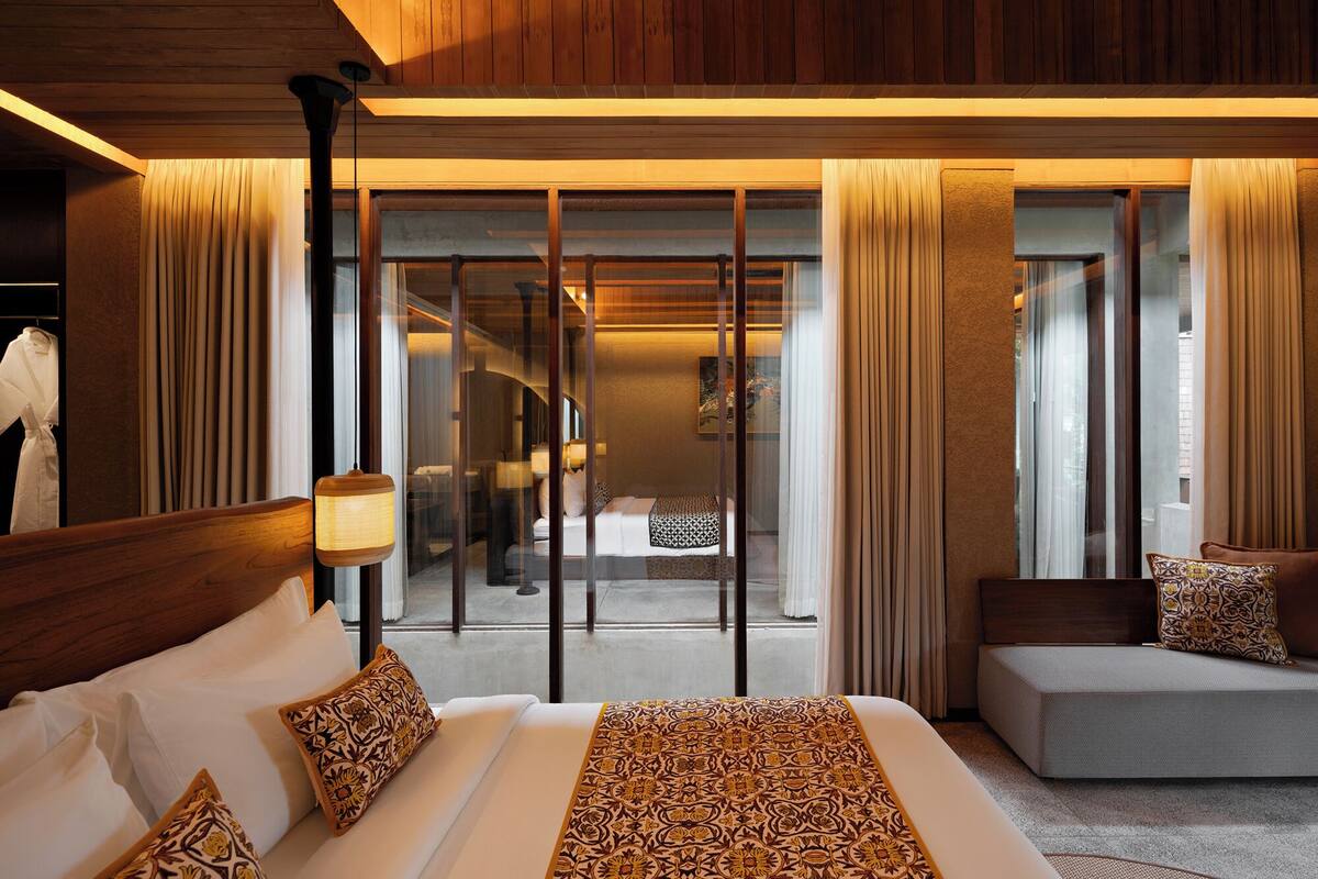 A hotel room with a large bed, a seating area, and a view through a glass door.