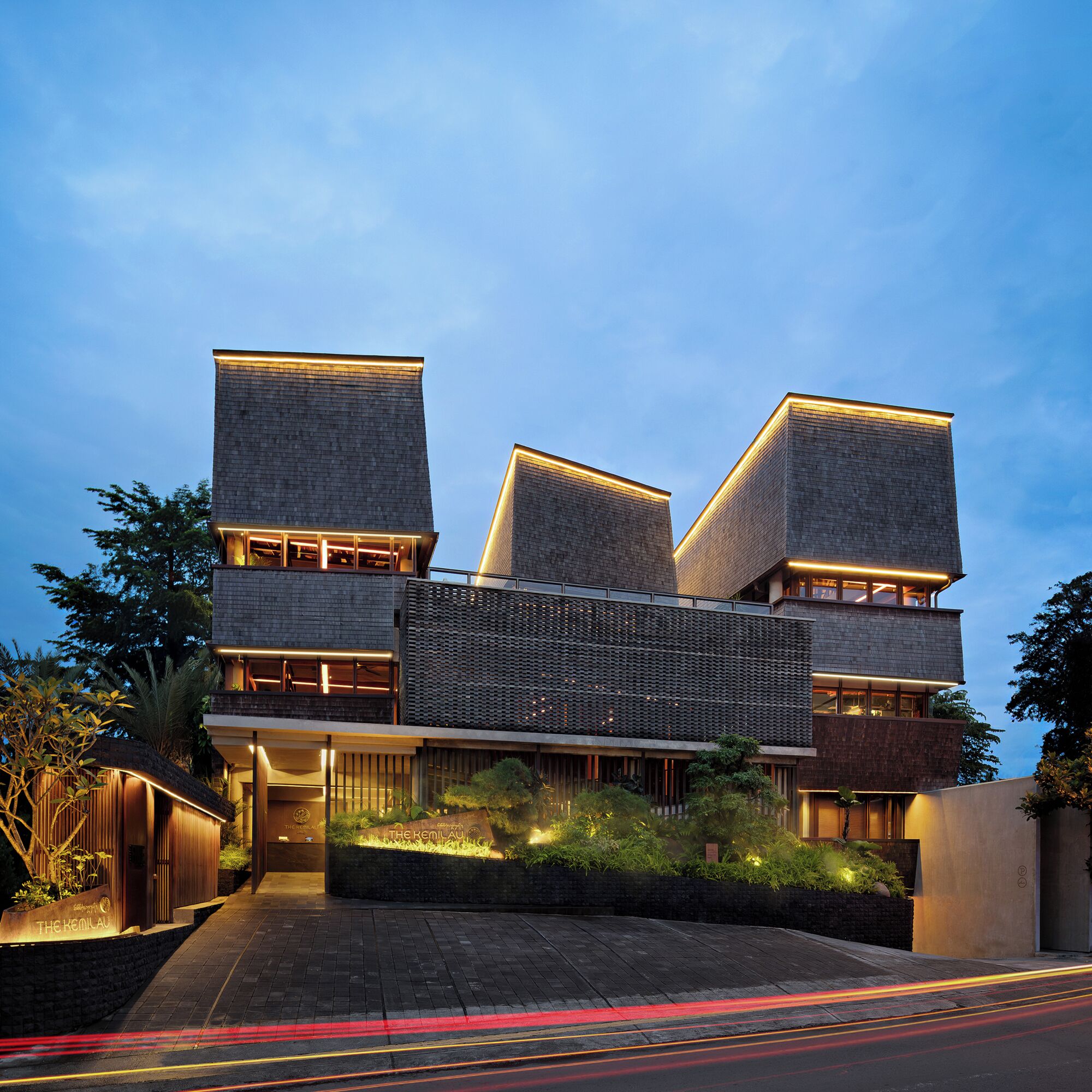 Een modern gebouw met een plat dak, grote ramen en een goed verlichte ingang.