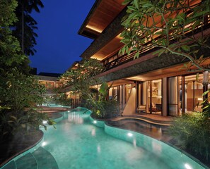 A modern resort with a swimming pool, lush greenery, and a well-lit building at dusk. - The Kemilau Ubud (Ubud)