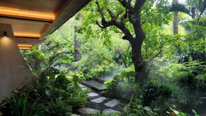 A lush indoor garden with a stone pathway leading through dense foliage. - The Kemilau Ubud (Ubud)