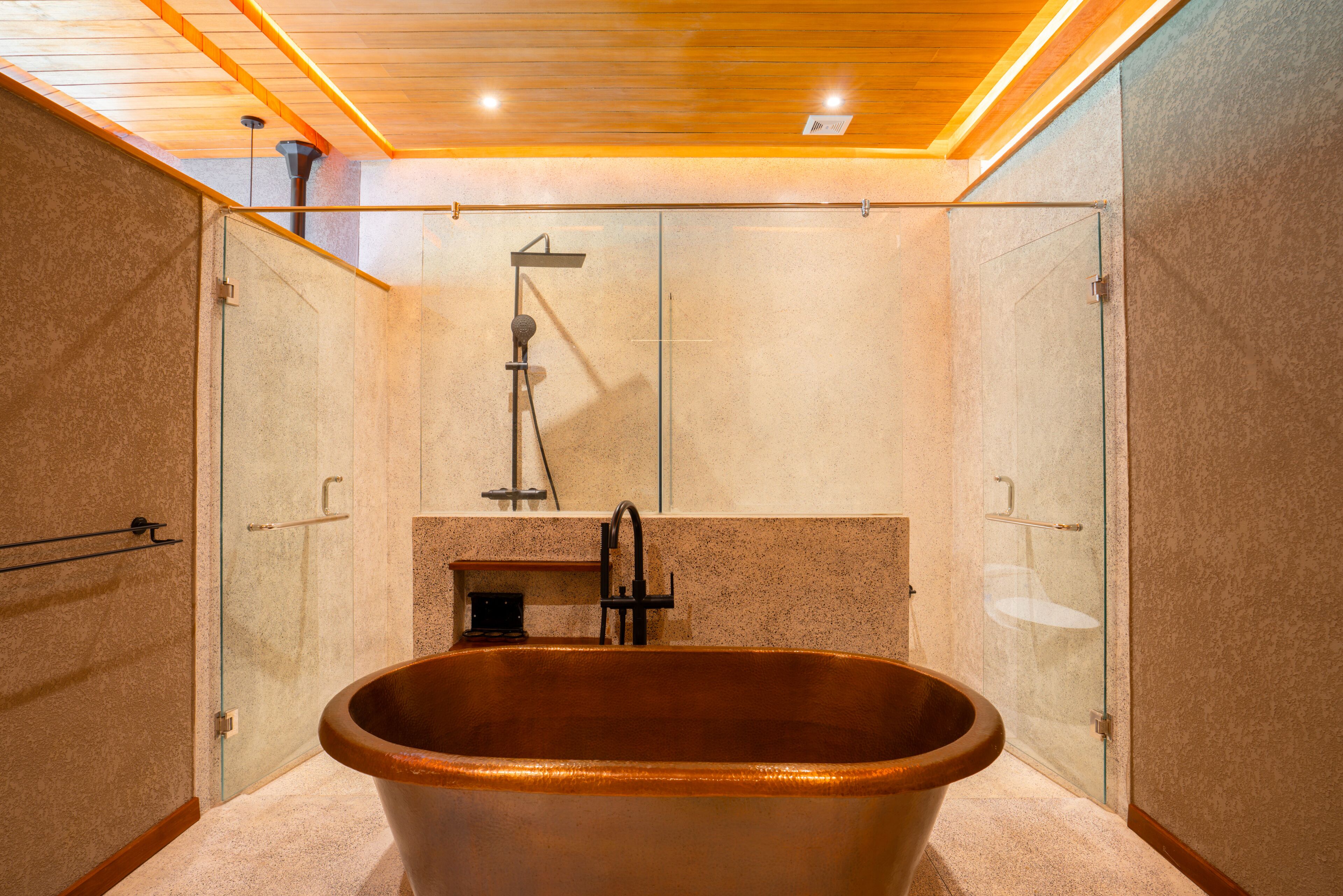 A modern bathroom with a freestanding bathtub, glass shower enclosure, and a wooden ceiling.