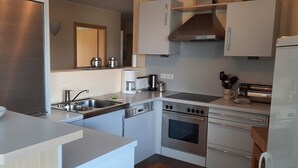 Een moderne keuken met roestvrijstalen apparatuur, een inbouwoven en een koffiezetapparaat.