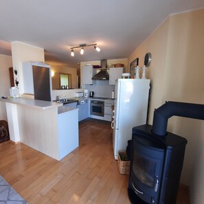 Une cuisine compacte dotée d’un îlot central, d’un four encastré, d’une cuisinière et d’un réfrigérateur.