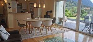 A modern kitchen with a dining area, a glass door leading to an outdoor patio with chairs.