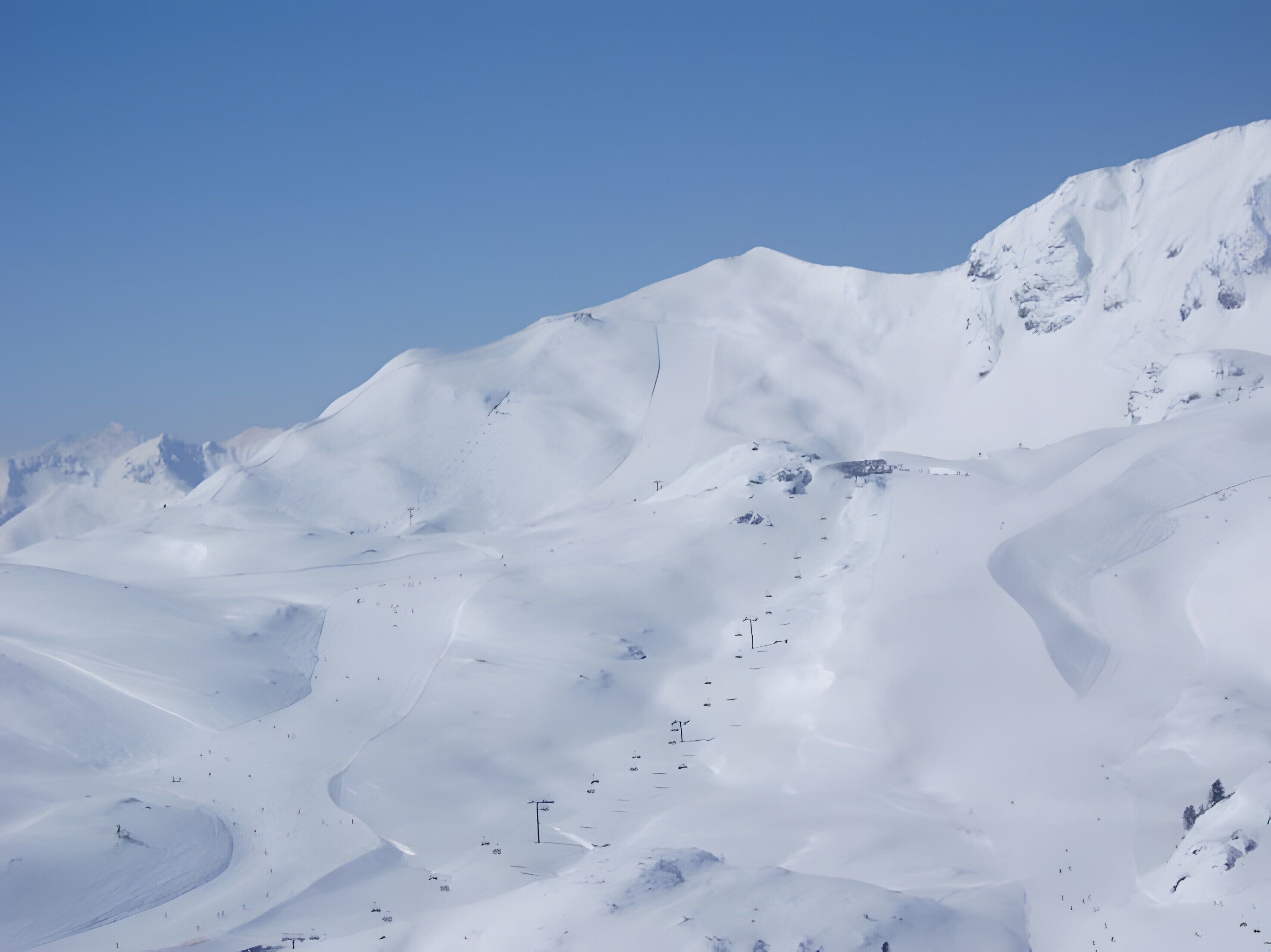 A snow-covered mountain with ski trails.