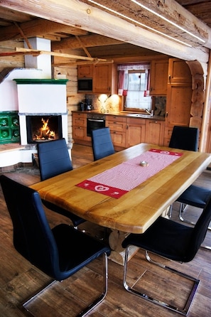 Un coin repas rustique, avec une cheminée, des meubles en bois et des chaises noires.