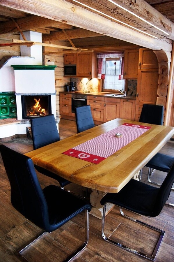 A rustic wooden dining area with a fireplace, wooden cabinets, and black chairs.