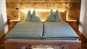 A bed with a checkered bedspread and pillows, wooden headboard, bedside lamps, and a wooden headboard with a branch decoration.