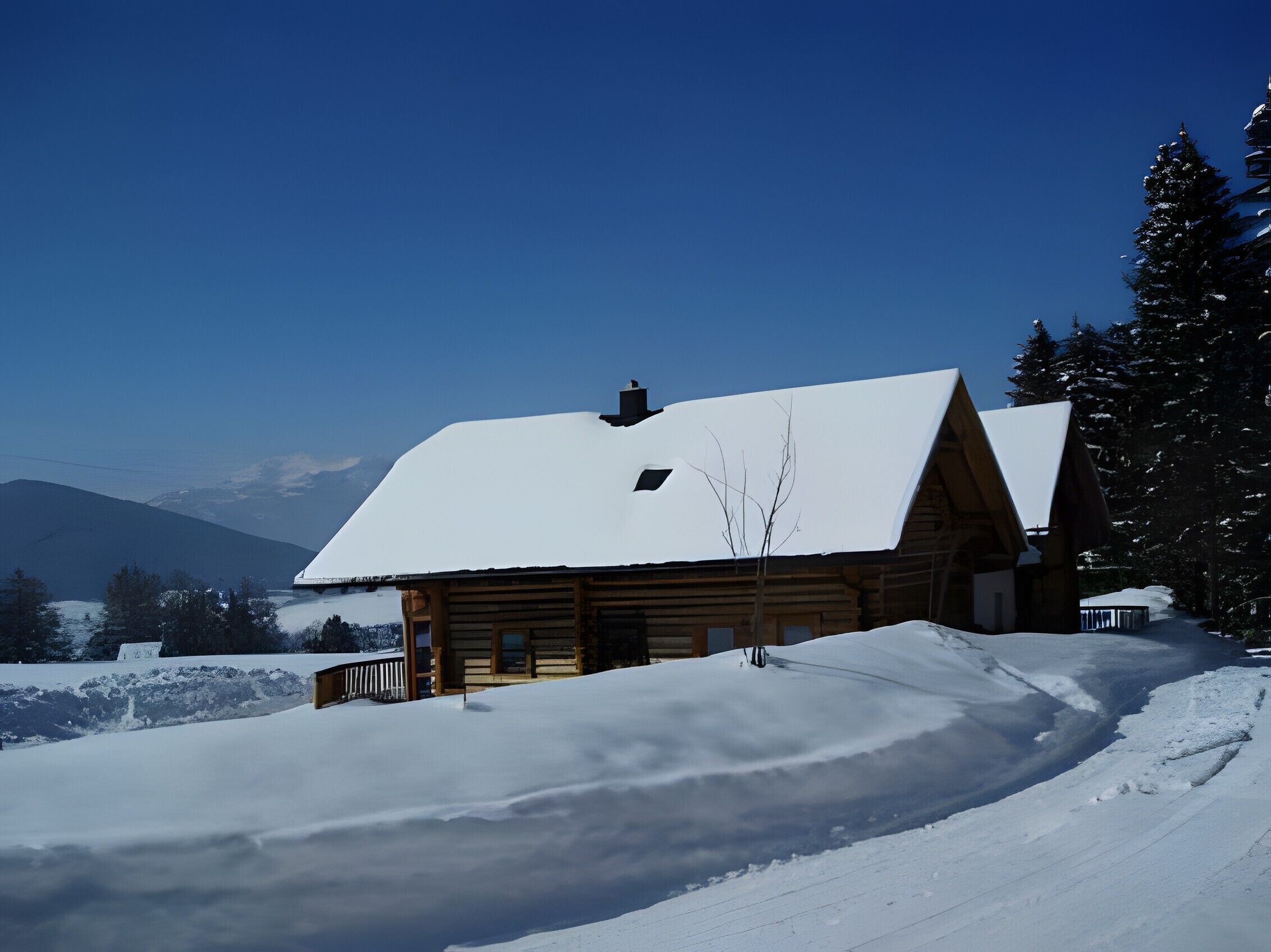 A log cabin with a snow-covered roof, surrounded by snow-covered ground and trees, with a clear sky in the background.