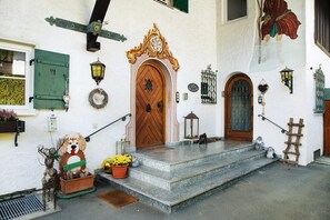 A building with a wooden door, steps, a dog sculpture, and a lantern. - Holiday Home 'Alpen Lodge' with Mountain View, Private Terrace and Wi-Fi (Garmisch-Partenkirchen)