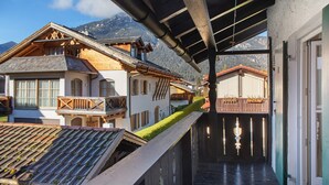A traditional chalet with a sloped roof, wooden balconies, and a view of mountains. - Holiday Home 'Alpen Lodge' with Mountain View, Private Terrace and Wi-Fi (Garmisch-Partenkirchen)