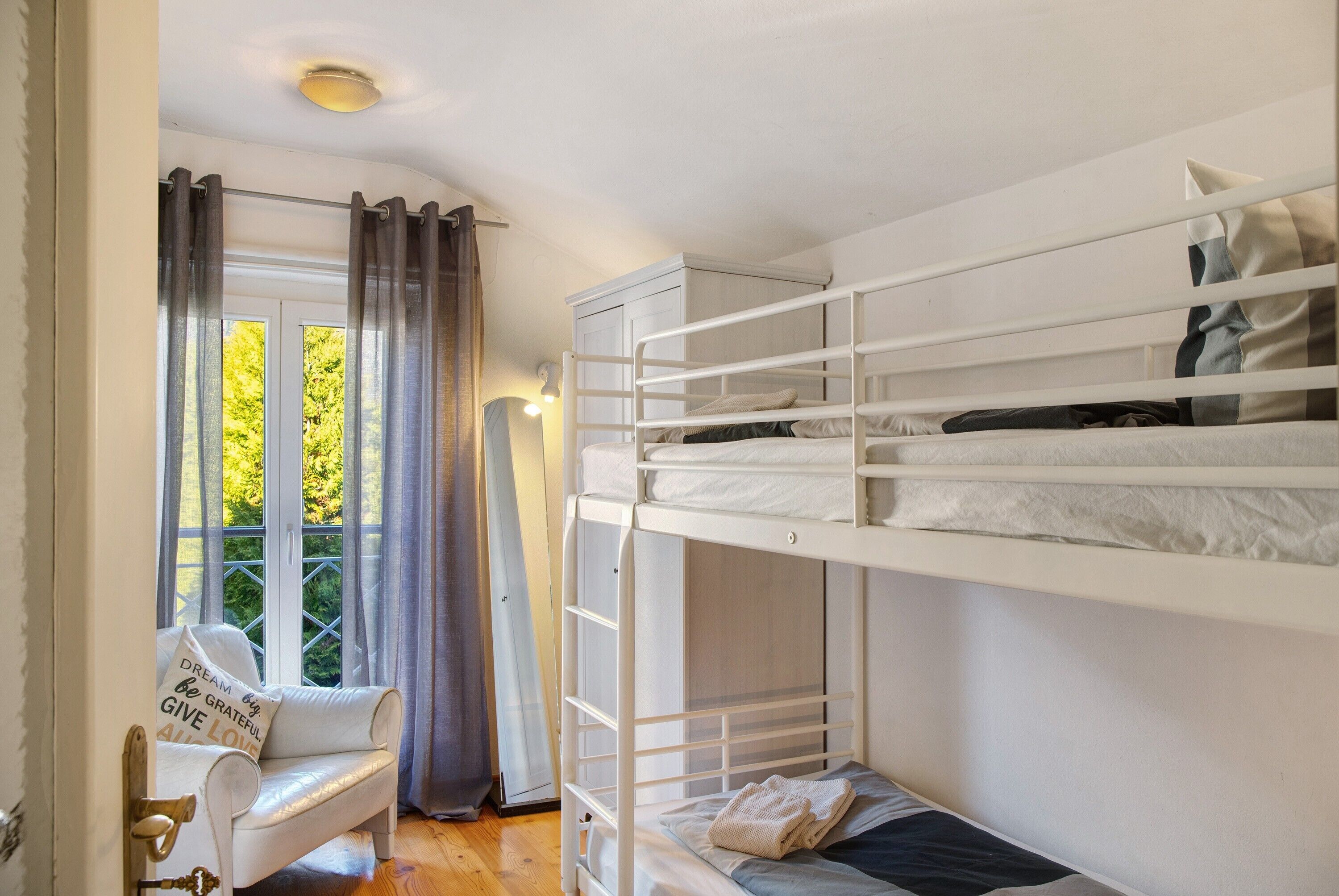 Une chambre avec un lit superposé, une fenêtre, des rideaux, un canapé et une porte avec une clé.